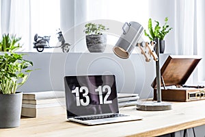 Close-up photo of laptop with clock screensaver placed on wooden
