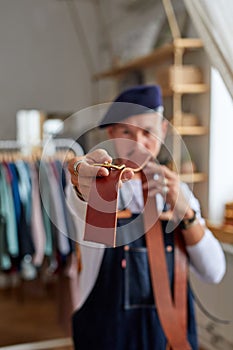 close-up photo of leather brown belt in hands of craftsman