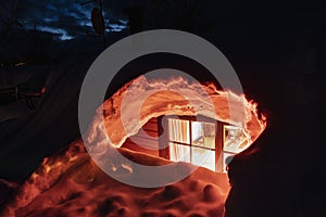 Close up photo of light window of mountain cabin fully buried under snow, view to inside room in house. Northern Sweden, Lapland,