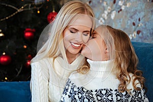 Close-up photo of little girl in knitted sweater kiss her mother