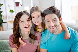 Close up photo of loving idyllic family little kid hug embrace her mommy daddy in house indoors