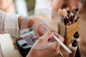 Close-up photo of make-up artist applying cosmetics on hand