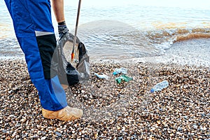 Close up photo of a man collecting garbage with a grabbing tool on the beach