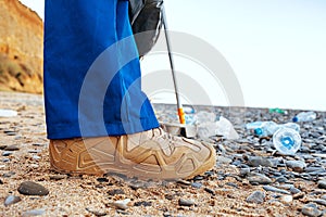 Close up photo of a man collecting garbage with a grabbing tool on the beach