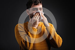 Close up photo of a man covering his nose with a handkerchief feeling bad and caught a cold, health care concept.