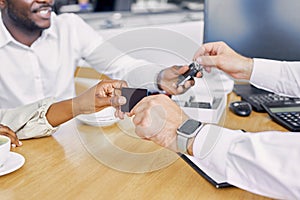 Close-up photo of man giving keys of car and his business card to customers