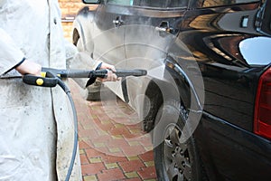 Close up photo of a man hands washes his car with a large head of water from a karcher on open air. photo