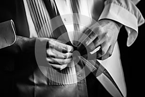 Close up photo of man putting on his tuxedo shirt.