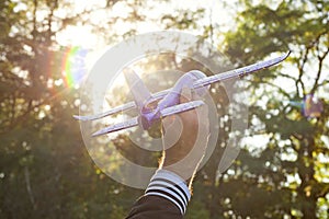 Close up photo of man`s hand holding toy airplane against blue sky. Airplane model in hand on sunny sky. Concepts of travel,