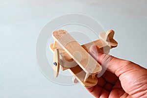 Close up photo of man's hand holding wooden toy airplane over wooden background. filtered image. aspiration and simplicity concept