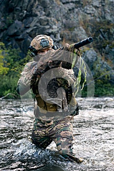 Close-up photo of a mercenary military sniper during a sabotage mission behind enemy lines - he stands knee-deep in the