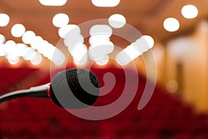 Close up photo of a microphone with blurred background & bokeh lights of auditorium with selective focus on microphone