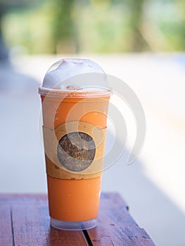 Close-up photo of milk iced tea in a plastic cup placed on a wooden table