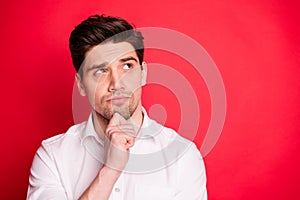 Close up photo of minded person touching his chin having thoughts wearing white shirt isolated over red background