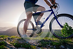 Close up photo from a mountain biker riding his bike  bicycle on rough rocky terrain on top of a mountain, wearing no safety