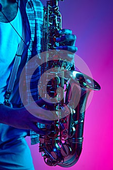 Close up photo of musician's hands playing jazz chord against pink-blue background in mixed neon light