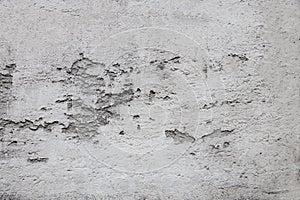 Close-up photo of old plaster on a white wall, which has fallen off in places due to time and weather conditions