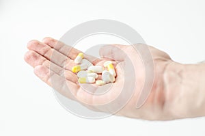 Close up photo of one round pill in young male hand. Man takes medicines with glass of water. Daily norm of vitamins, effective dr