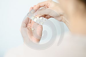 Close up photo of one round pill in young male hand. Man takes medicines with glass of water. Daily norm of vitamins, effective dr