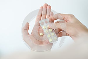 Close up photo of one round pill in young male hand. Man takes medicines with glass of water. Daily norm of vitamins, effective dr