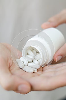 Close up photo of one round pill in young male hand. Man takes medicines with glass of water. Daily norm of vitamins, effective dr