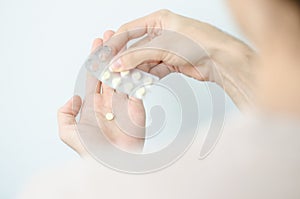 Close up photo of one round pill in young male hand. Man takes medicines with glass of water. Daily norm of vitamins, effective dr