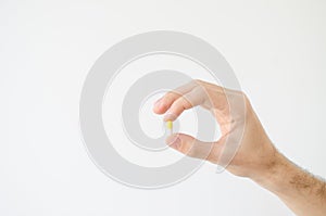 Close up photo of one round pill in young male hand. Man takes medicines with glass of water. Daily norm of vitamins, effective dr