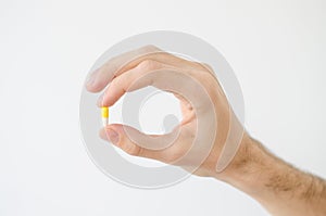 Close up photo of one round pill in young male hand. Man takes medicines with glass of water. Daily norm of vitamins, effective dr