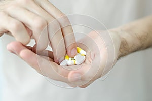 Close up photo of one round pill in young male hand. Man takes medicines with glass of water. Daily norm of vitamins, effective dr