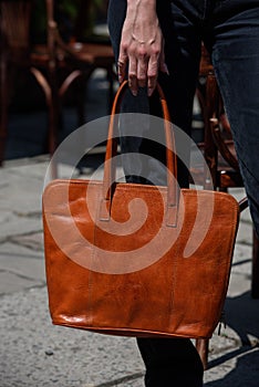 close-up photo of orange leather bag in a woman& x27;s hand