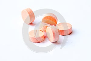 Close-up photo of orange pills isolated on white background