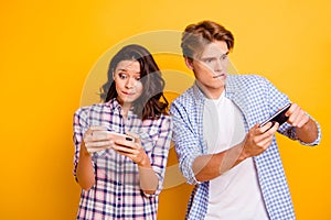 Close up photo of pair teenagers he him his she her lady boy with telephones in arms amazed with playing video games