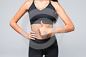 Close up photo of perfect fit slim woman`s belly and thumb up on gray background photo