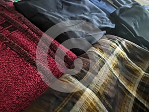A close-up photo of a pile of clothing with someone holding a cell phone. This asset is suitable for fashion websites.