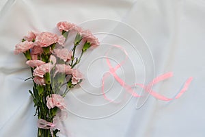 Close up photo of a pink carnation bouquet and a number 8 shapped ribbon  over white background