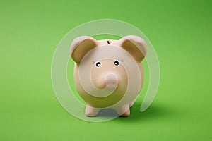 Close up photo of pink piggy money bank on bright green wall background. Money accumulation, investment