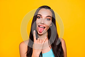 Close up photo of playful girlish feminine young rocker sticking tongue out with fingers horned showing her love for