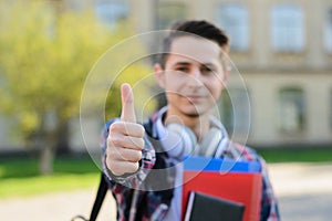 Close-up photo portrait of cheerful optimistic nice handsome cool self-assured guy holding copybooks in hands and making finger up