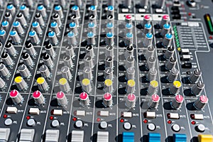 Close up photo of a professional sound mixer with many adjustments, knob switches and buttons of audio mixer control panel.