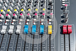 Close up photo of a professional sound mixer with many adjustments, knob switches and buttons of audio mixer control panel.