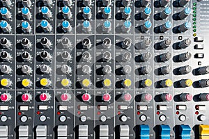 Close up photo of a professional sound mixer with many adjustments, knob switches and buttons of audio mixer control panel.