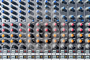 Close up photo of a professional sound mixer with many adjustments, knob switches and buttons of audio mixer control panel.