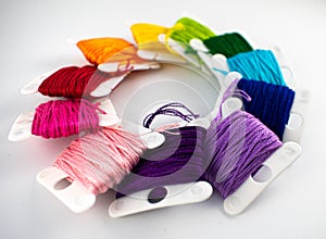 Close up photo of rainbow embroidery thread on bobbins