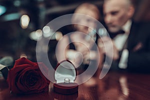 Close up photo of ring and rose on table