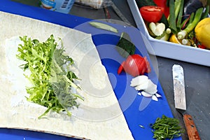 close up photo of roll cooking with arugula leafs, onion tomato,paprika, lemon closeup photo with knife