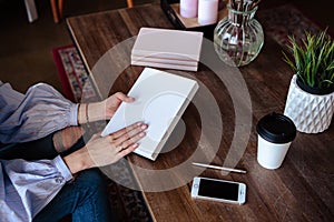 Close-up photo of scheduler notebook on a wooden table. Female hand writes on paper.