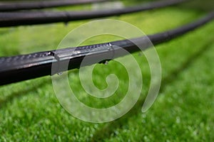 Close up photo with selective focus of drip irrigation system on the green lawn