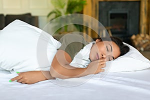 Close up picture of a sleeping asian woman. She lies under blanket and hugs the pillow.