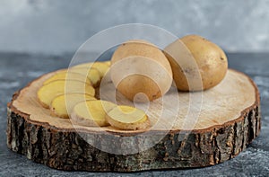 Close up photo of Sliced and whole potatoes on wooden board