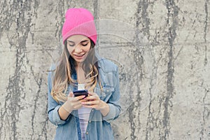 Close-up photo of smiling hipster girl reading text on smartphone. She is very happy because she got an invitation to a party cell